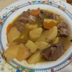 Plato de estofado de carrillera de ternera con trozos de patata cocida y zanahoria en salsa.