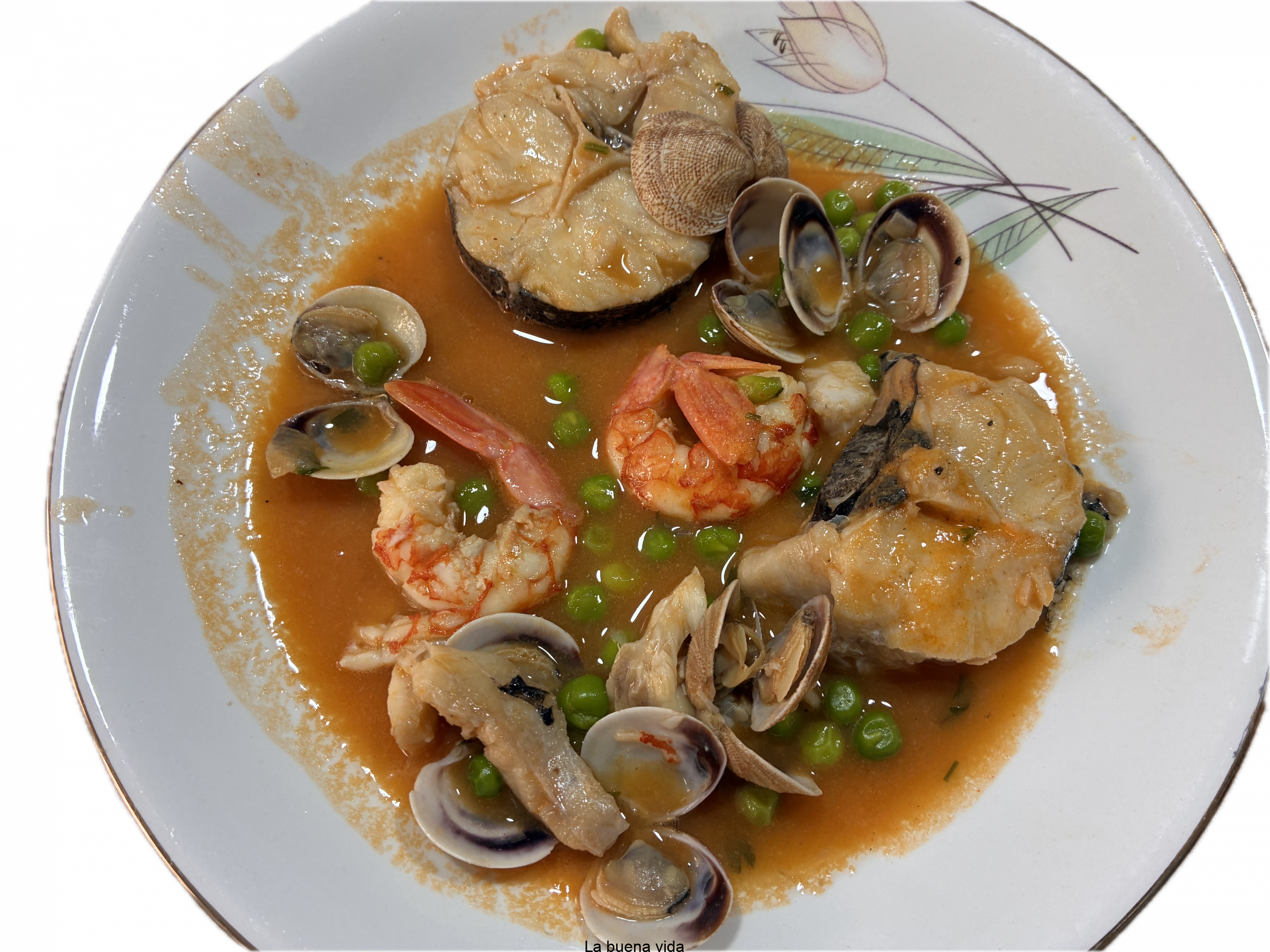 Plato hondo con medallones de merluza en una salsa anaranjada, acompañados de almejas abiertas, langostinos pelados y guisantes