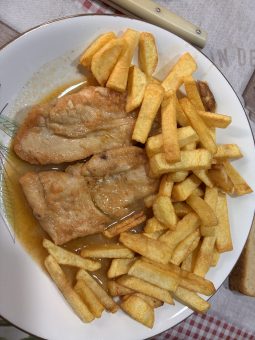 Cazuela con trozos de pollo guisado en una salsa espesa de pimentón, con hojas de laurel y ajos picados.